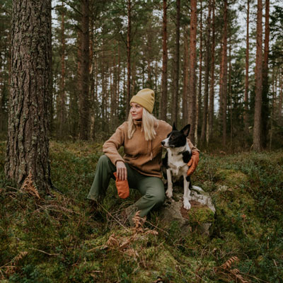 Frau mit Hund sitzen im Wald und machen eine Pause vom Wandern